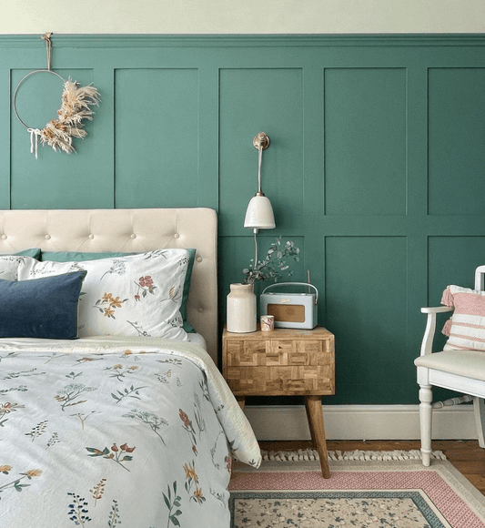 Green shaker wall panelling behind bed